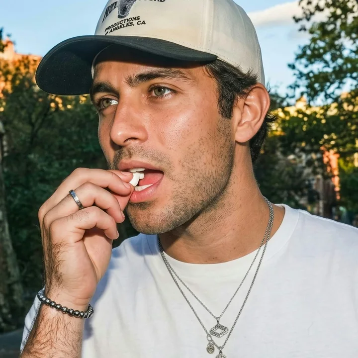 Man placing a pouch under his upper lip outdoors